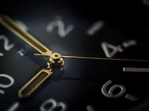 A close view of a watch dial with gold hands and numerals on a dark navy face