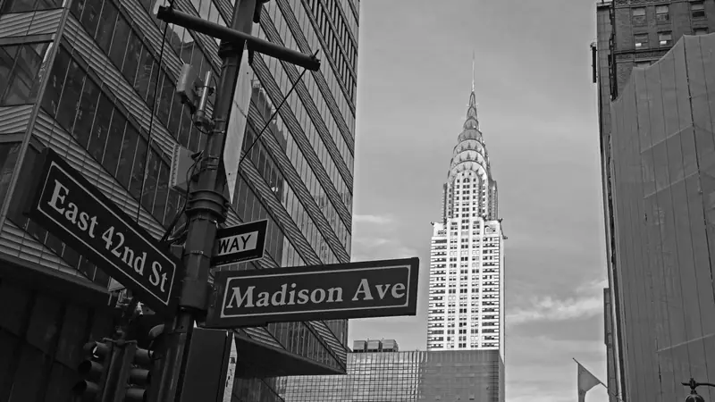 Street signs reading Madison Avenue and East 42nd Street with the Chrysler Building rising behind them in Midtown Manhattan
