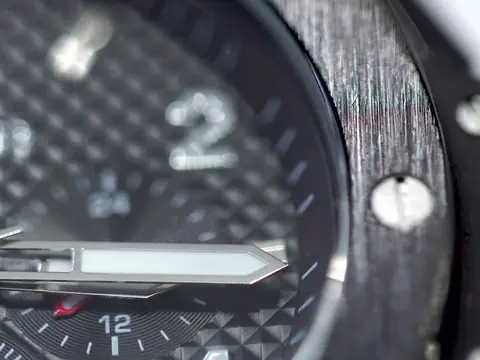 A close view of a wristwatch with a textured dark dial and a bezel held by exposed screws