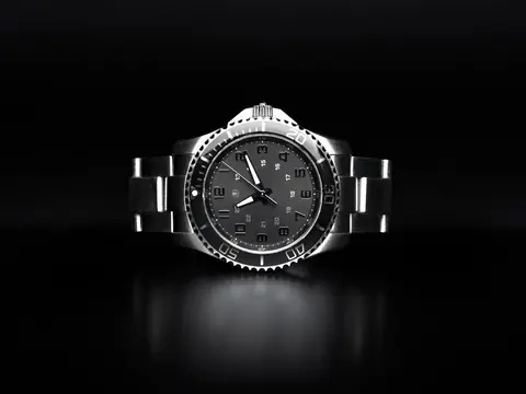 A steel sports wristwatch with a black dive bezel and a metal bracelet on a black background
